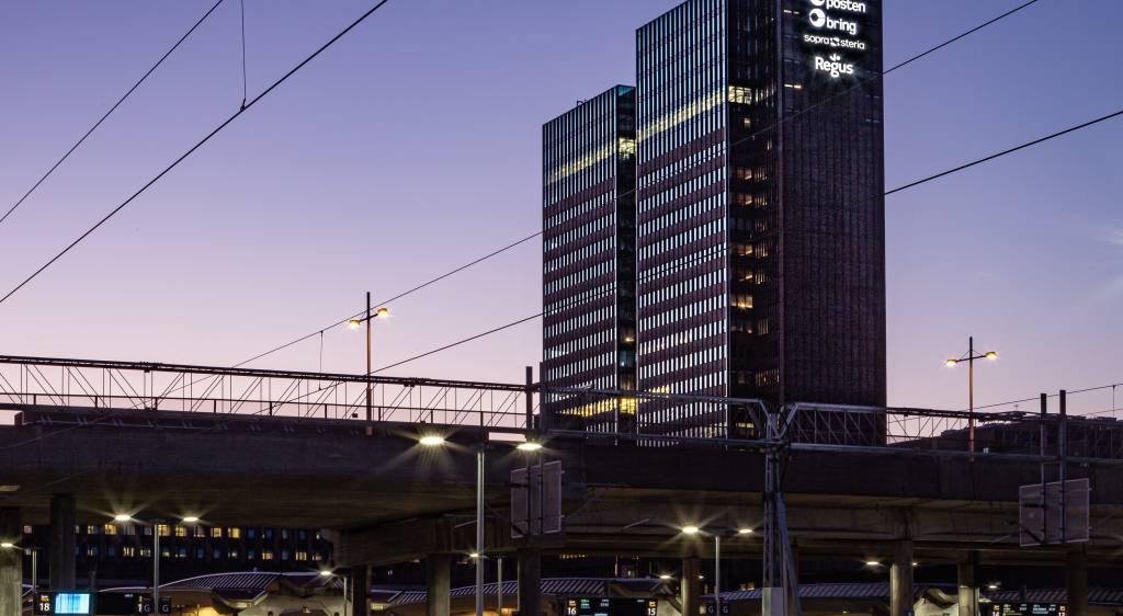 Posten Bring sine logoer vil lyse fra toppen av Posthuset også de neste ti årene. Foto: Entra / magent.no