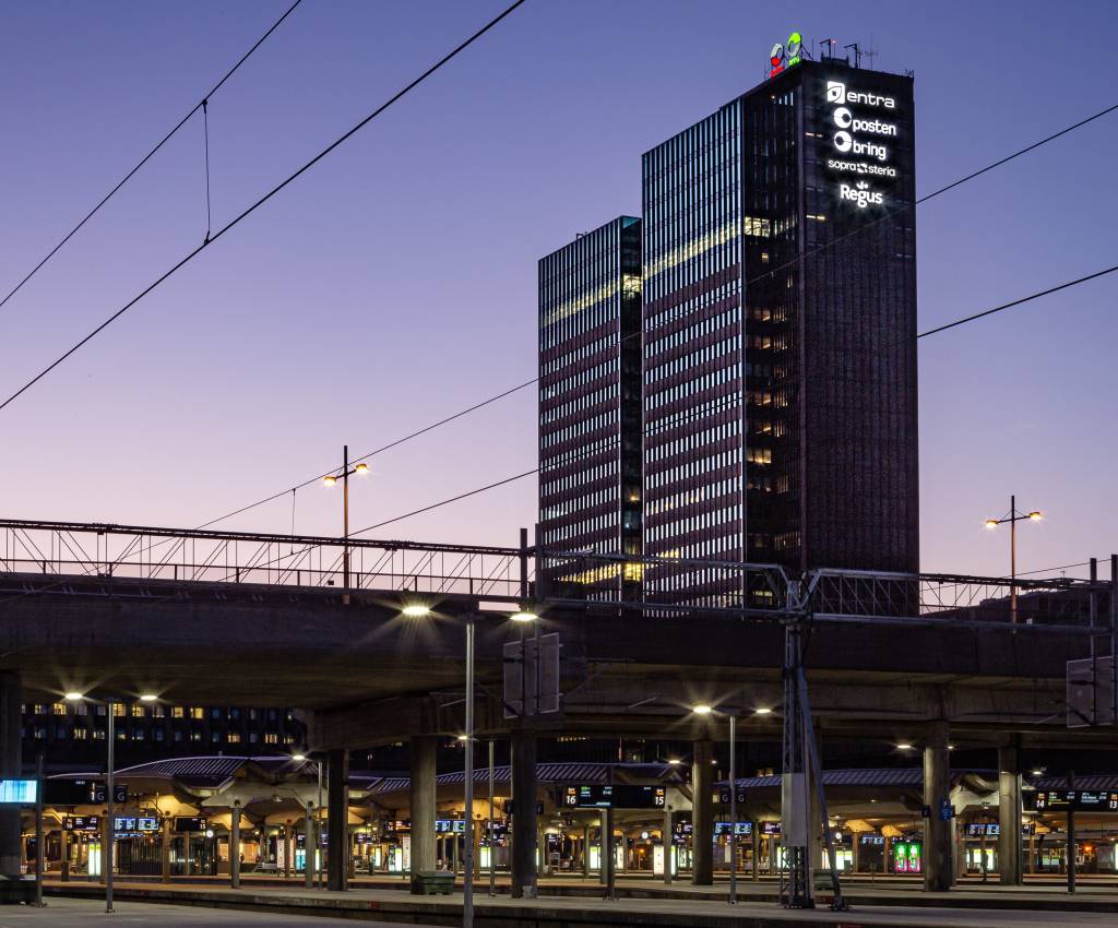 Posten Bring sine logoer vil lyse fra toppen av Posthuset også de neste ti årene. Foto: Entra / magent.no